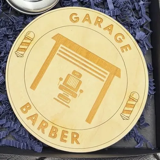 Gravēts koka disks ar Garage Barber zīmi&nbsp;– garāžas vārti un bārbera krēsls